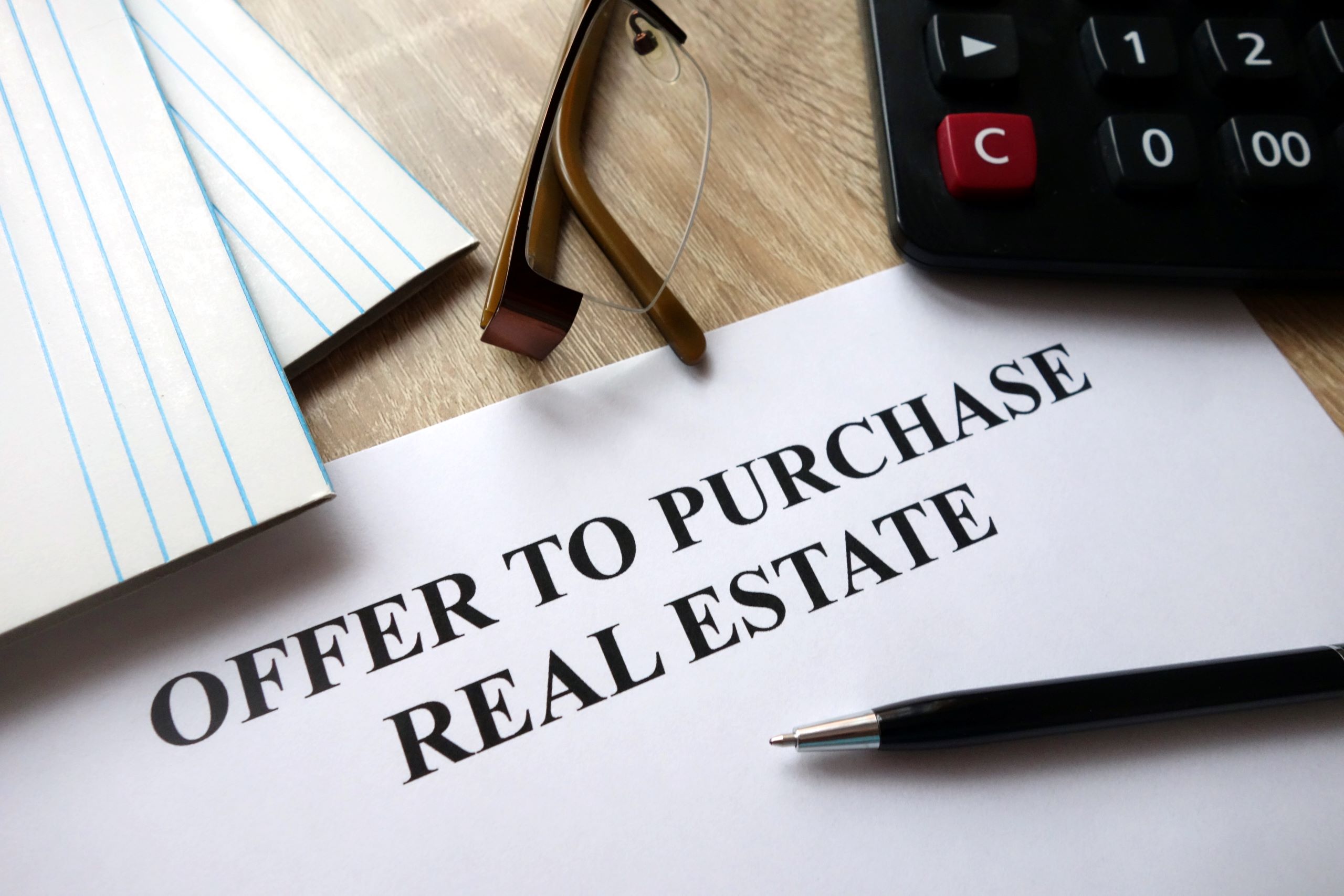 Offer to purchase real estate with pen, calculator and glasses on desk