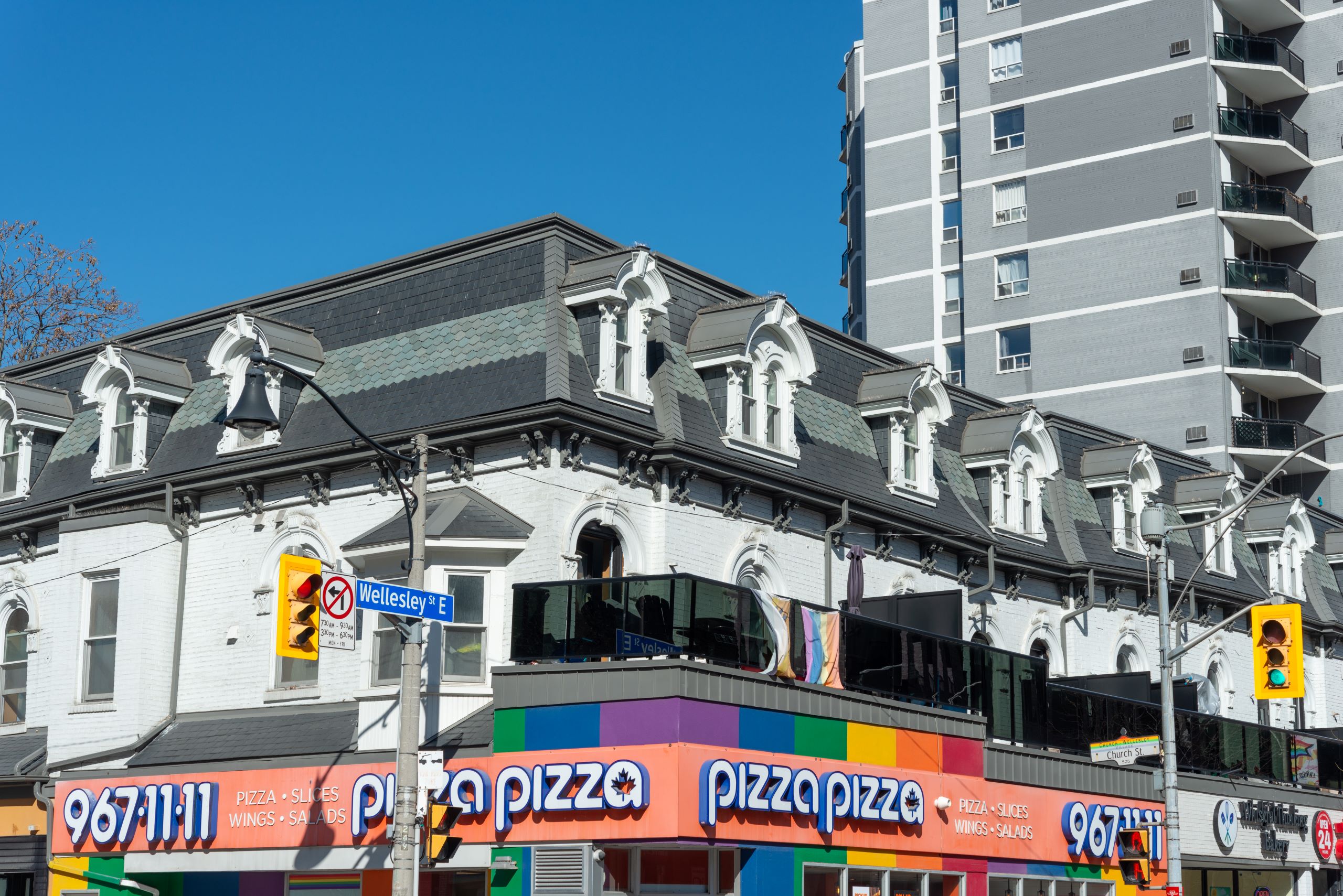 exterior building facade and sign for pizza pizza, a pizza restaurant chain, located at 68 Wellesley Street East (north east corner at Church Street) in Toronto, Canada